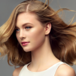 Blonde woman with curly beautiful hair on gray background.