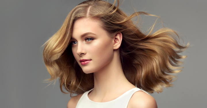 Blonde woman with curly beautiful hair on gray background.